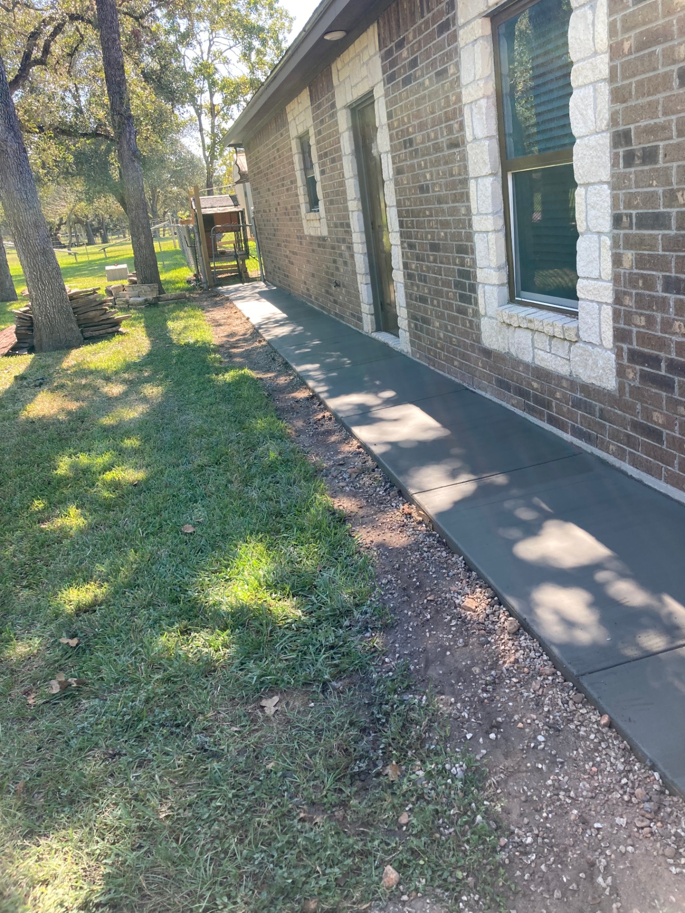 Finished smooth concrete sidewalk running alongside a brick home