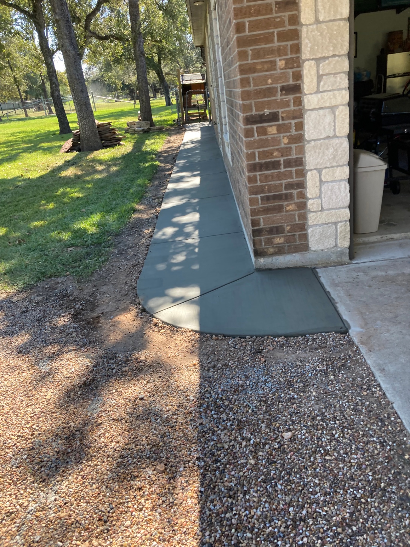 Smooth poured concrete walkway with curved edge tying into a garage slab