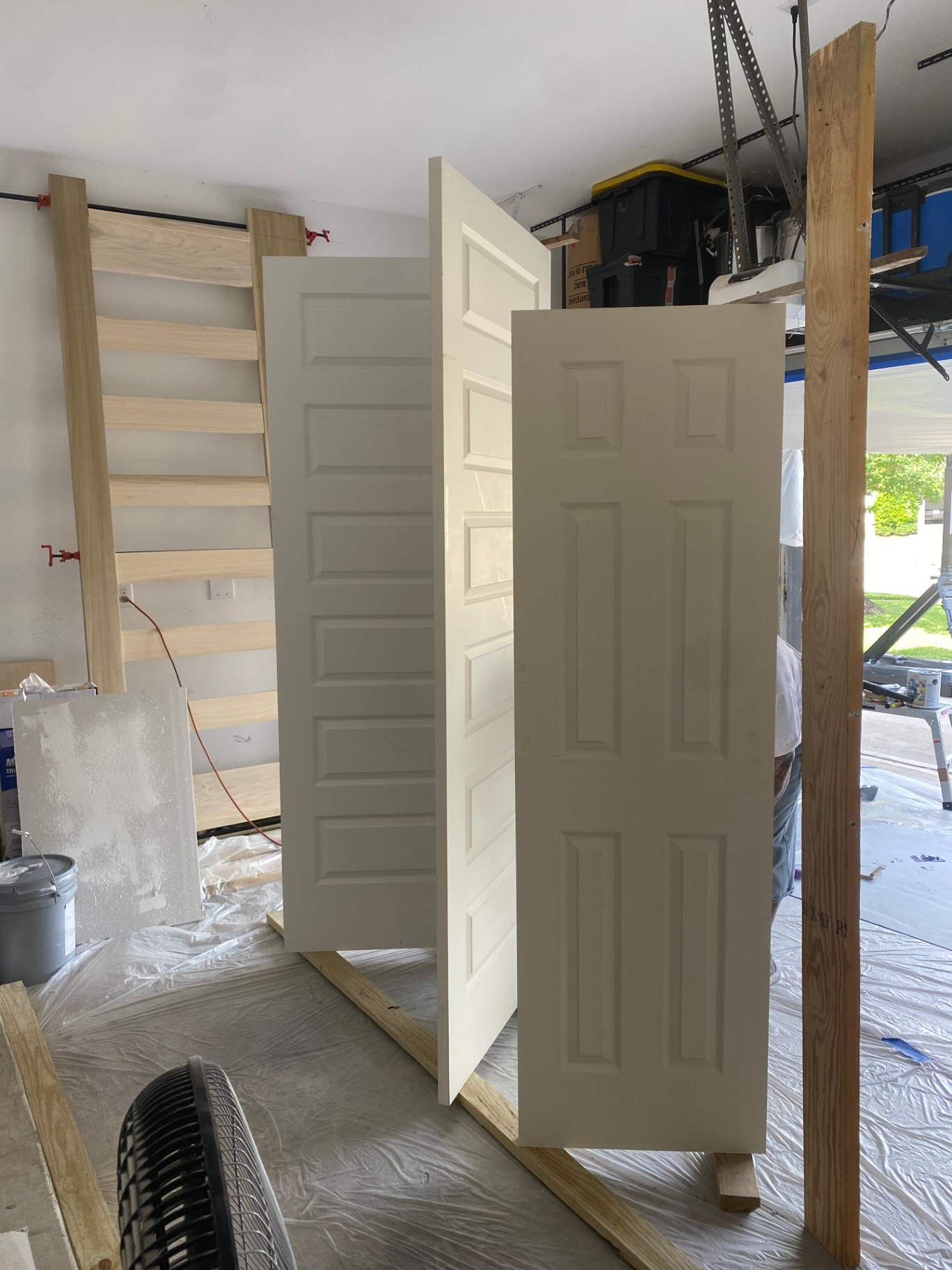 Closet doors being painted and dried in a garage workspace