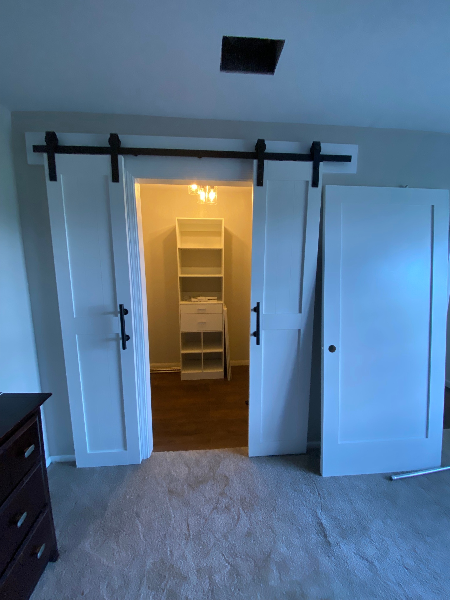 White sliding barn doors installed over a closet opening with custom storage inside
