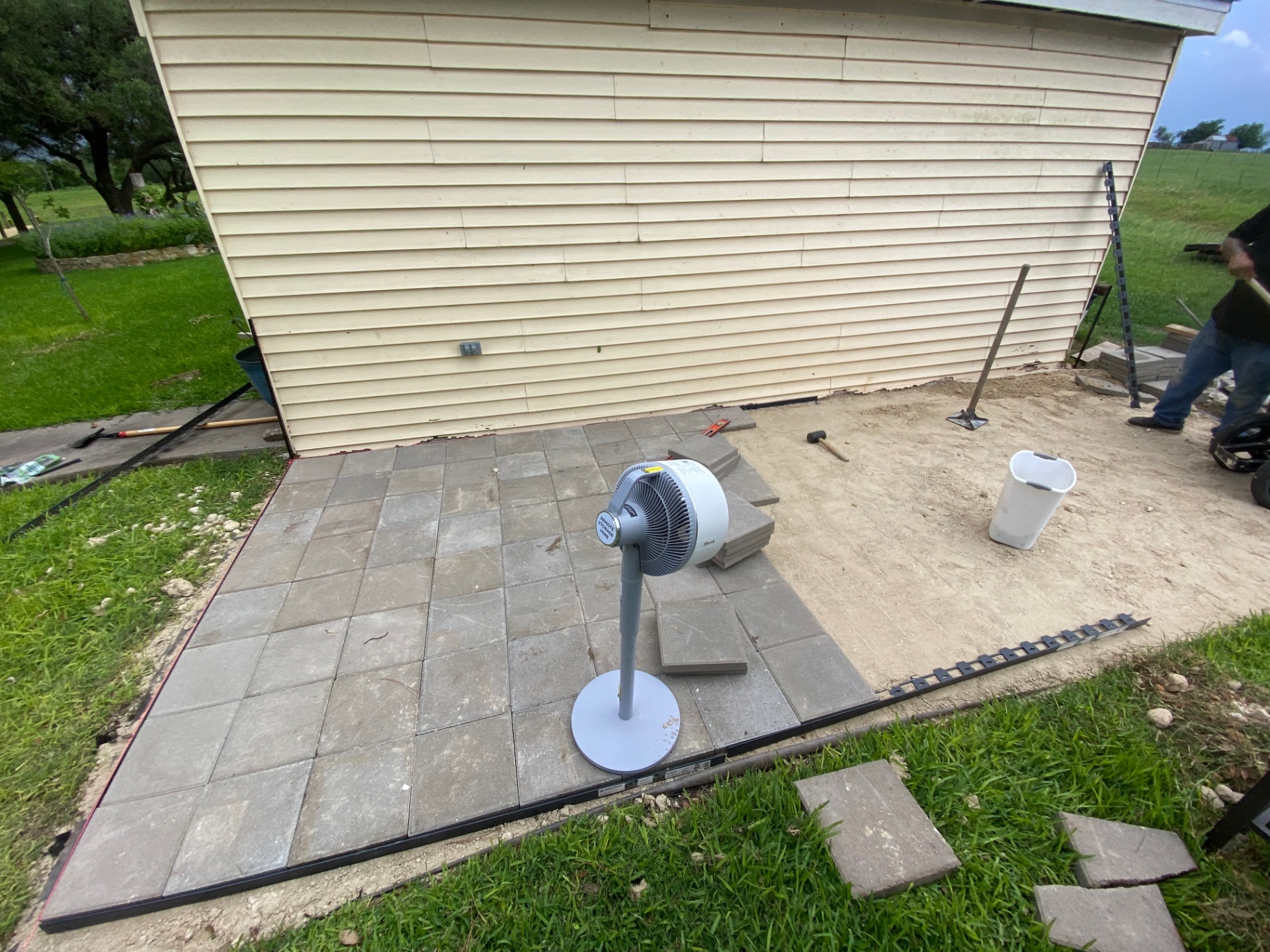 Paver patio installation in progress with square stones being set in place