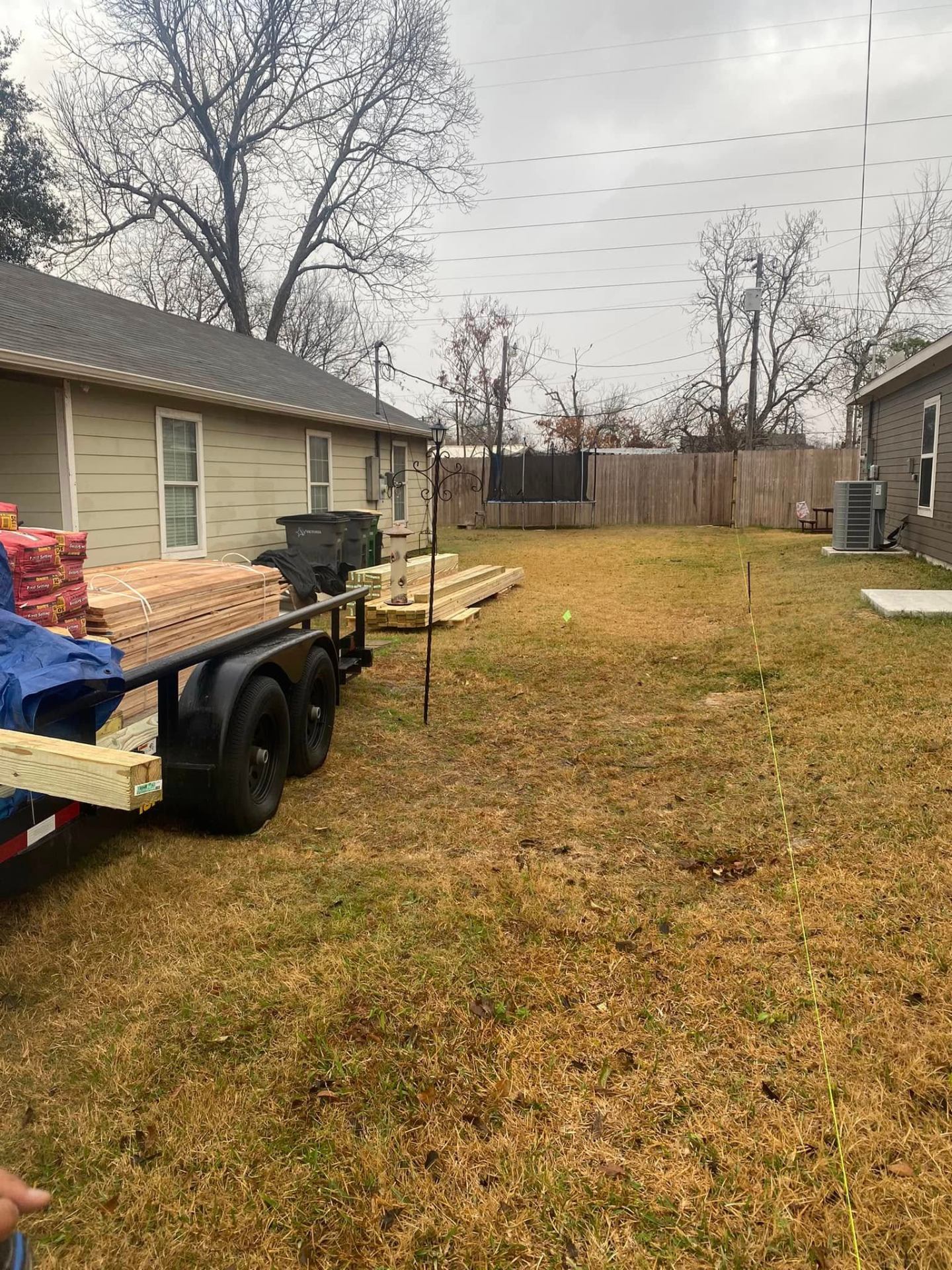 Backyard staked out and lumber delivered for a new wood privacy fence in Victoria TX