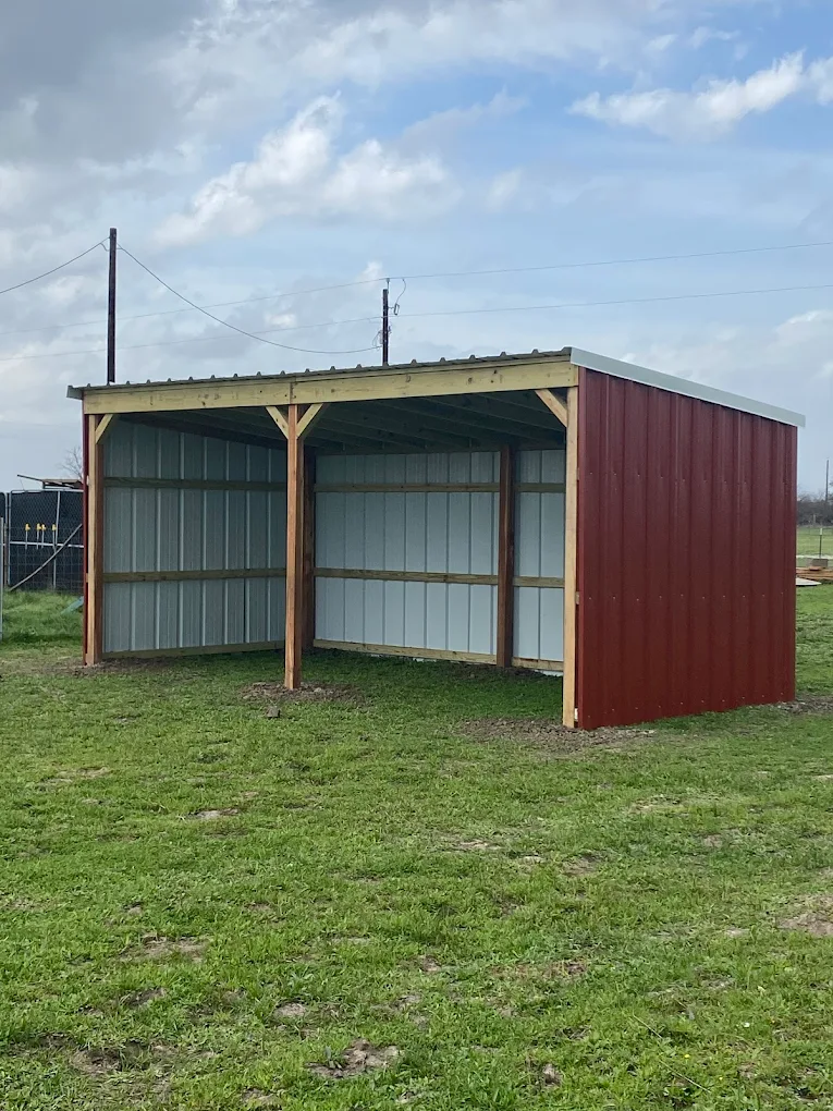 Red metal livestock loafing shed built on a South Texas pasture