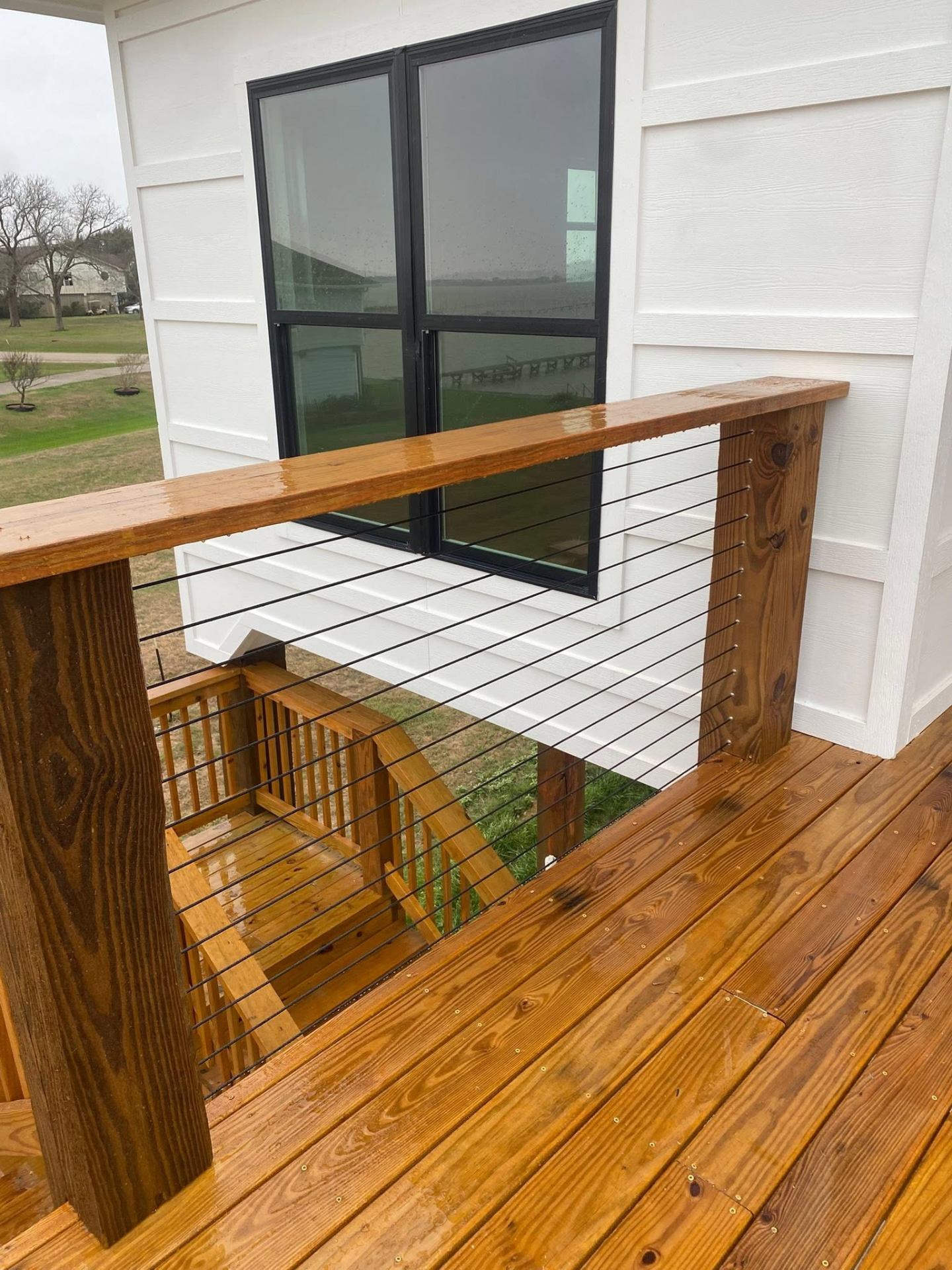 Stained wood deck with cable railing and stair opening
