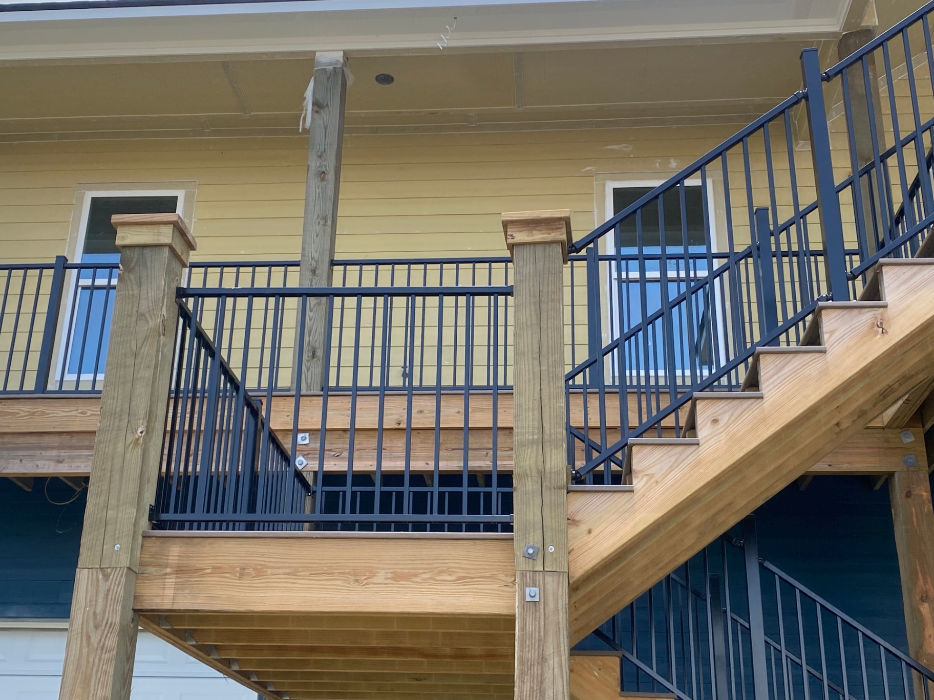Close view of custom deck stairs and black metal railing system on an elevated build