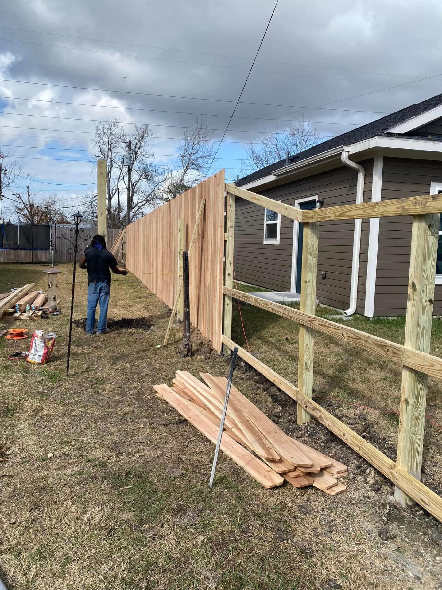 Cedar privacy fence being installed on pressure-treated framing between two homes