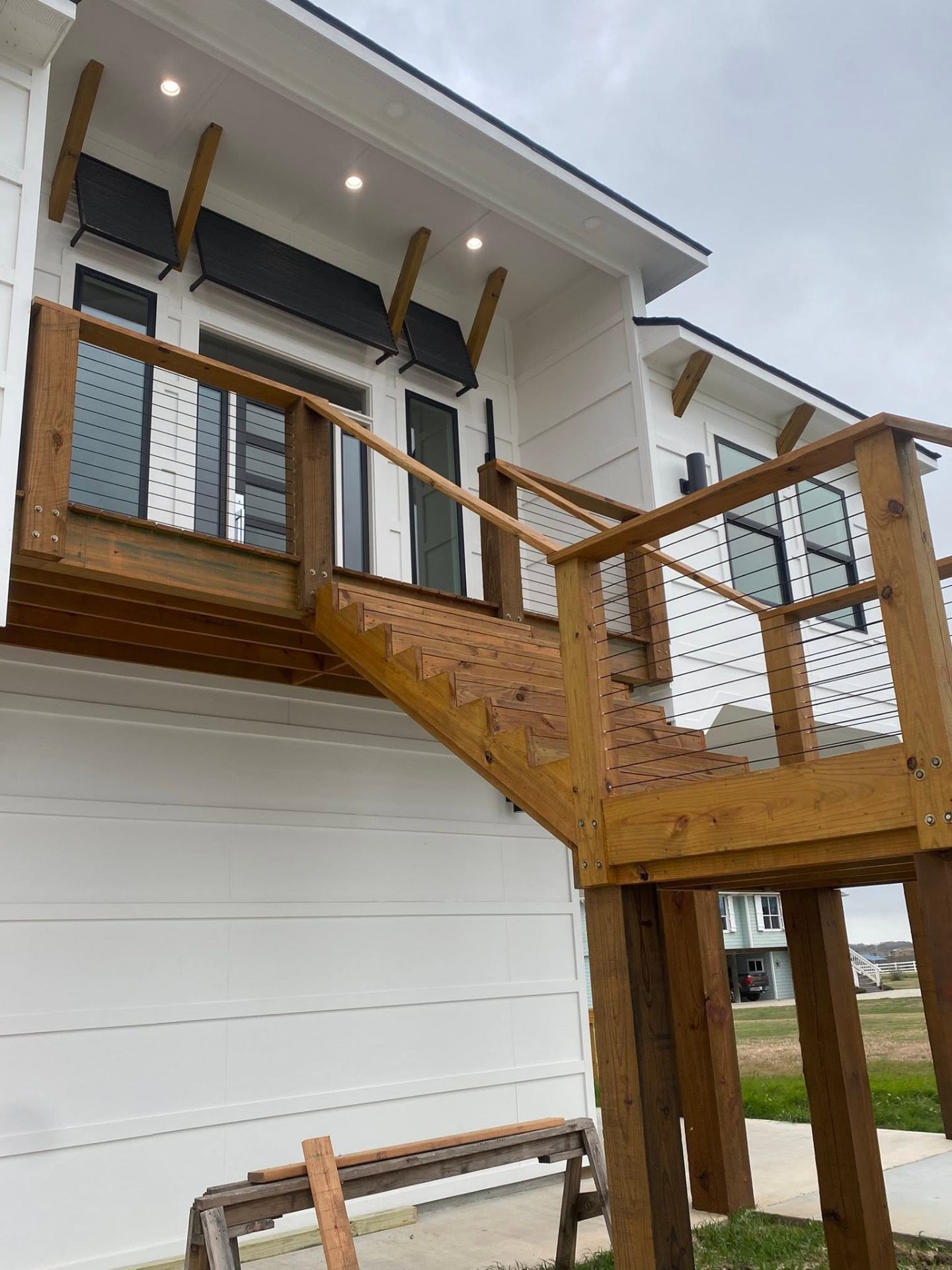 Two-story custom deck with stairs and cable railing on a modern farmhouse
