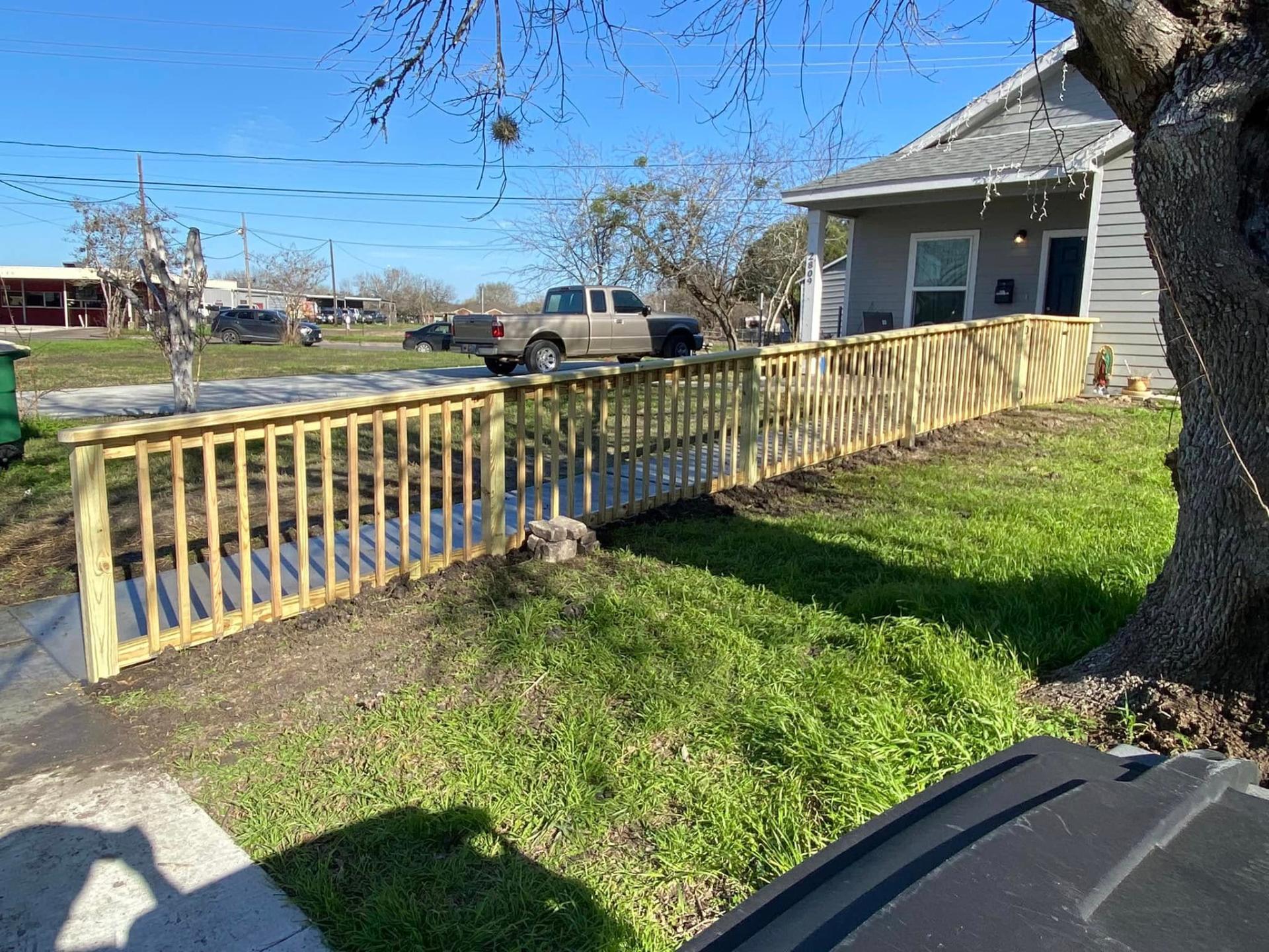 New pressure-treated picket fence along a front yard in Victoria TX